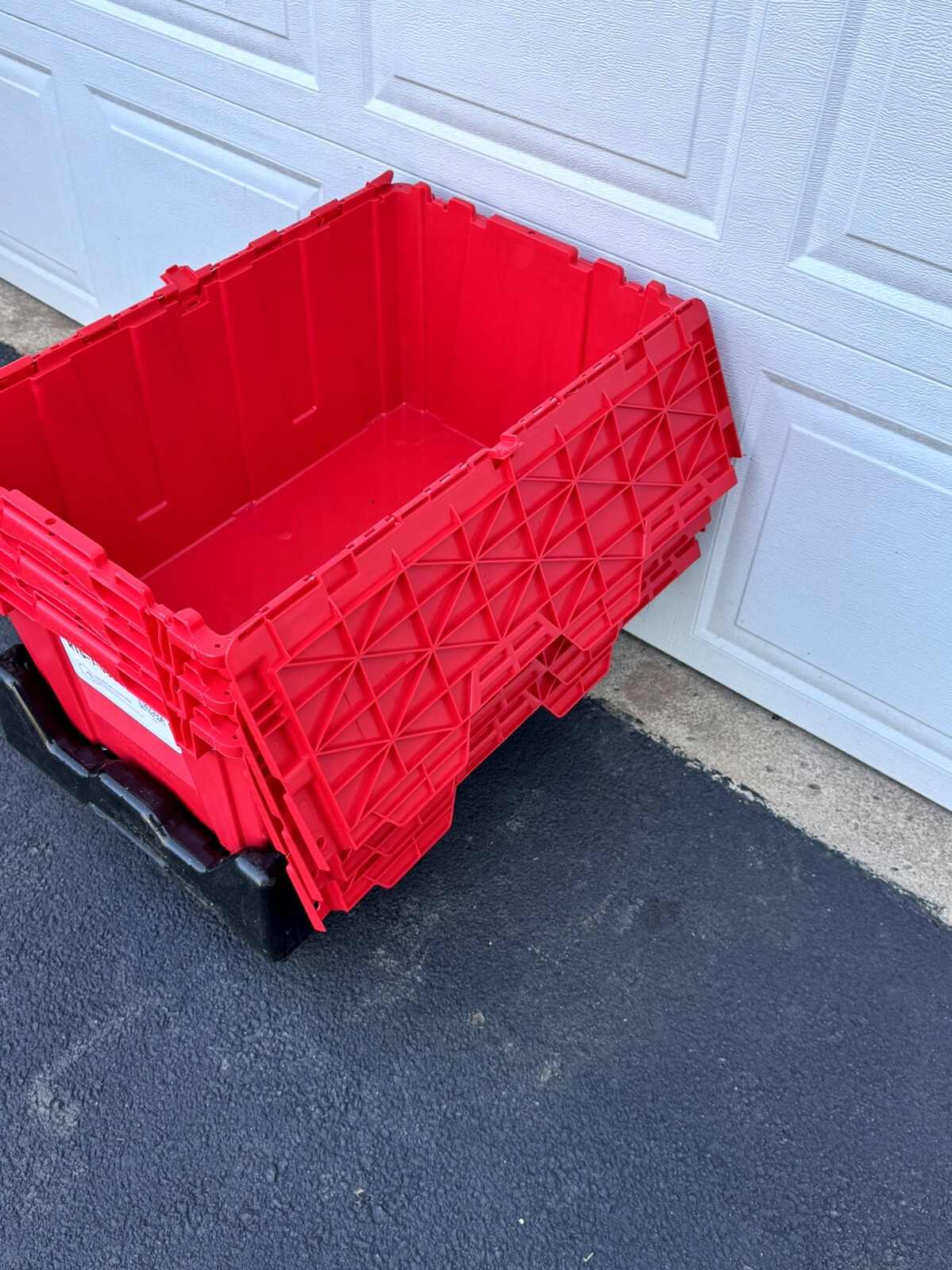 Three empty red totes nested inside each other on a black dolly
